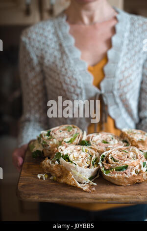 Rolls with tuna and greens on the wooden board in the woman`s hands Stock Photo
